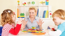 Preschool: Young smiling teacher discussing with group of children. Learning and having fun. Selective focus to teacher talking.